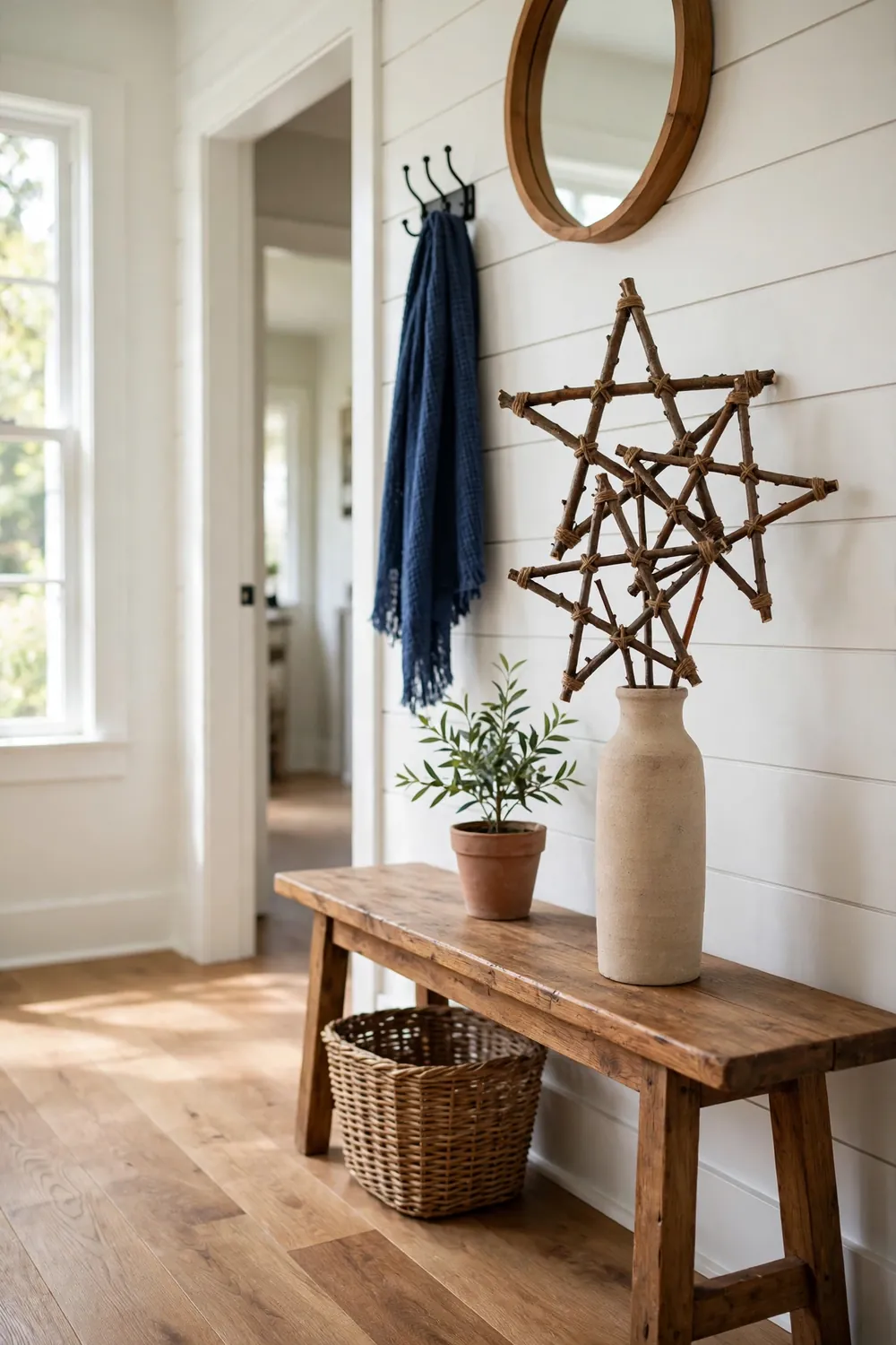 Handmade twig stars tied with twine displayed in a tall vase on a wood bench in a rustic entryway